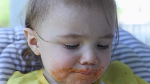 彼女は口の中に食べ物を置くために指を使用するように顔にソースと幼児のクローズビュー — ストック動画