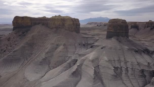 ユタ州のヘンリー マウンテンズに向かって風景レイヤーを見る砂漠の崖を越えて飛行する空中ビュー — ストック動画