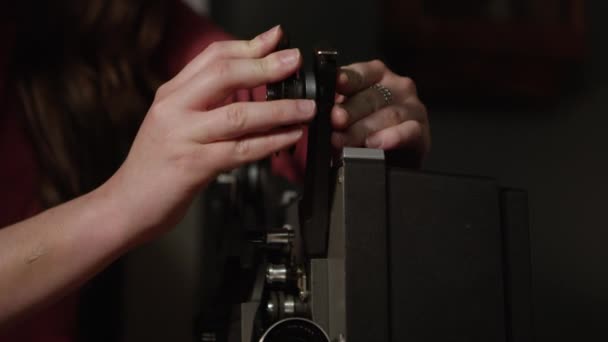 古いプロジェクターにフィルムリールを置く人は カメラでフィルムを供給します — ストック動画
