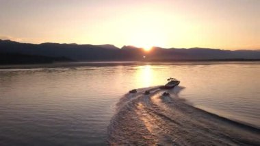 Tekne etrafında dörde doğru renkli günbatımı sırasında tüpler üzerinde insanları çekerek tekne aşağıdaki havadan görünümü.