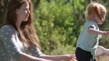 Toddler annenden başka bir yetişkin öpmek için sonra geri anneler kollarını onun kucağında oturmak için geliyor.