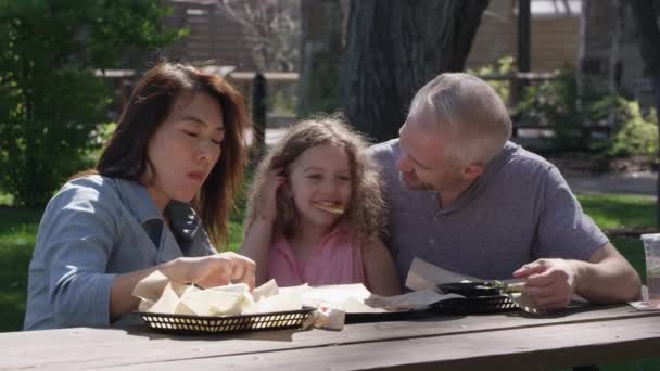 Familia Riendo Mientras Hace Picnic Como Hija Tiene Comida Colgando — Vídeos de Stock