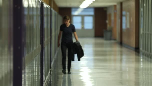 10代の若者は ジャケットの過去のロッカーを運ぶ空の学校の廊下に一人で歩く — ストック動画