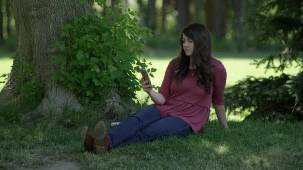 Mujer Joven Sosteniendo Teléfono Celular Mientras Está Sentada Parque Mientras — Vídeos de Stock