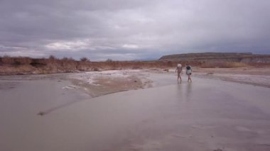 İki genç kadın Utah bulutlu bir gün çölde nehirde yürüyüş.