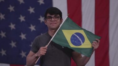Amerikan Bayrağı'nın önünde duran Adam Brezilya Bayrağını tutuyor.