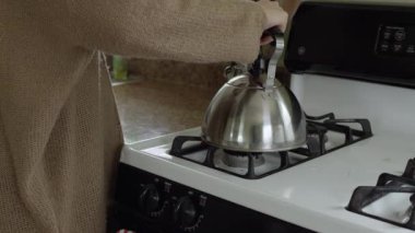 Çaydanlık için sobayı aydınlatan kadının yakın görünümü sonra uzaklaşıyor.