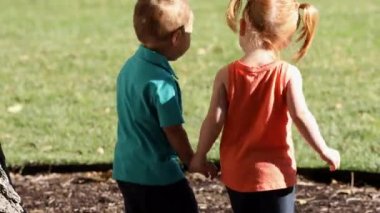 İki çocuk yürürken ve el ele tutuşurken elini çeker ama kız çimenlerin içine girerken onu tekrar yakalar..