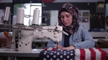 Irak kökenli Amerikalı kadın Amerikan Bayrağı dikiyor yukarı bakıp gülümsüyor.
