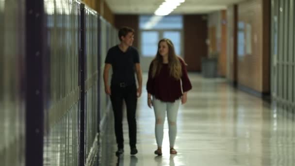 彼らは空の学校のロッカーに沿って話すように2ティーンエイジャーは 学校の廊下を歩いて — ストック動画