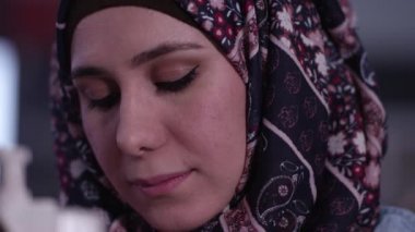 Yukarı bakıp gülümserken başörtüsü takan etnik kadının yakından görünümü.
