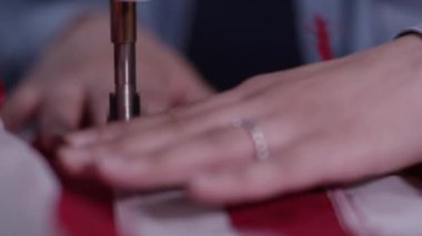 Üretim sırasında dikiş makinesi ile Amerikan Bayrağı besleyen ellerin yakın görünümü.