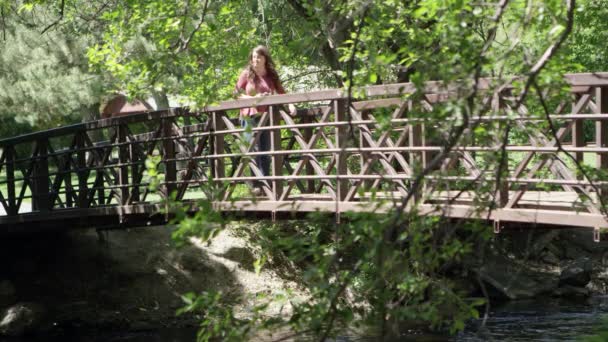 Μια Γυναίκα Που Περπατάει Στη Γέφυρα Και Σταματάει Για Πάρει — Αρχείο Βίντεο