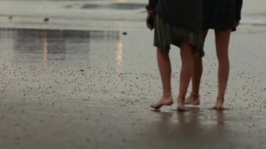 Sahilde yürüyen iki kişinin yanından geçerken sadece bacaklarını ve ayaklarını görmeleri.