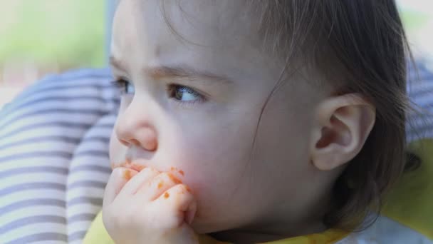 바깥에서 식사를 하면서 얼굴과 음식으로 바라보는 유아의 클로즈업 — 비디오