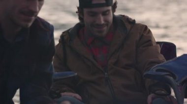 Açık havada yanan ateşin yanında dinlenen bir grup genç