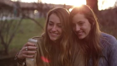 İki ikiz kız kardeş açık havada cep telefonu kullanıyor