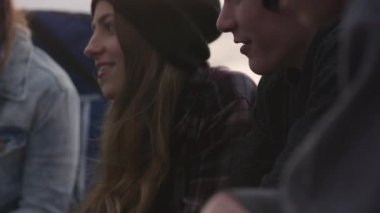 Açık havada yanan ateşin yanında dinlenen bir grup genç