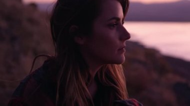 Genç güzel kız dağlarda oturuyor ve düşünüyor.