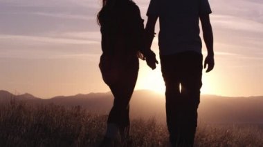 Birbirine aşık genç bir çift gün batımında dağlarda dinleniyor.