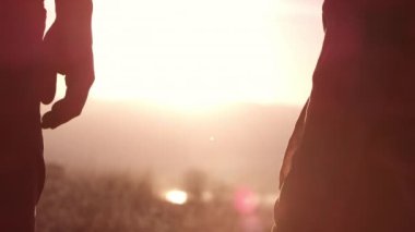 Birbirine aşık genç bir çift gün batımında dağlarda dinleniyor.