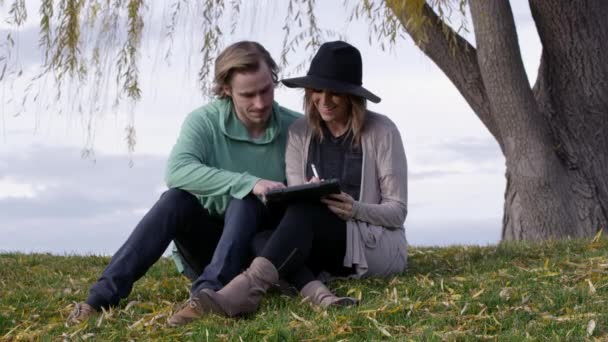 Jeune Couple Caucasien Utilise Ipad Sous Grand Arbre — Video