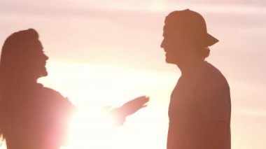 Birbirine aşık genç bir çift gün batımında dağlarda dinleniyor.