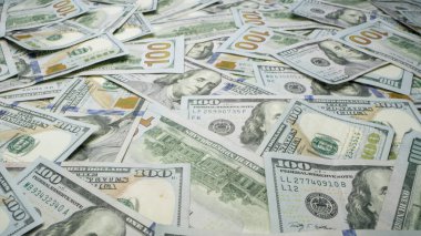 Masanın üstüne dağılmış 100 dolarlık banknotlar yığını..