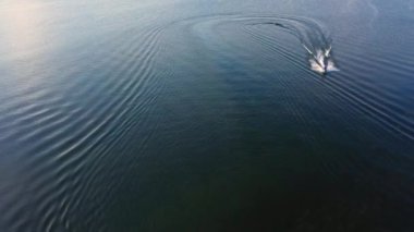 Hebgen Gölü 'nde suyun üzerinde oynayan bir tekneyi arkadan çeken kişinin hava görüntüsü..