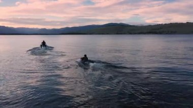 Gün batımında Hebgen Gölü 'nde diz çökerken insanları suya çeken bir su aracı..