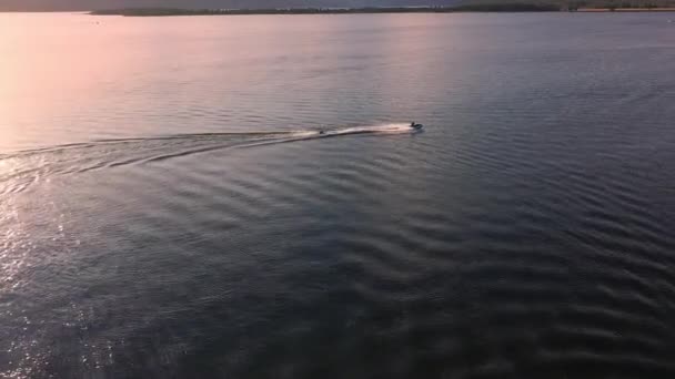 日没時に湖で遊ぶ際に背後に人を引く水上機の上の空中の景色 — ストック動画