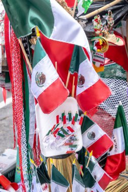 A bunch of flags with a Mexican flag in the middle. The flags are decorated with candles and are hanging on a pole