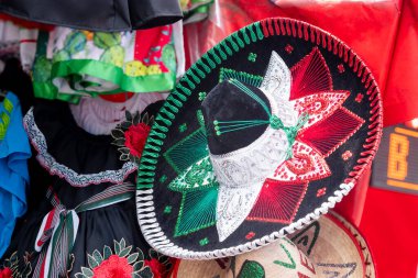 A colorful Mexican hat is displayed on a table. The hat is decorated with red, white, and green colors