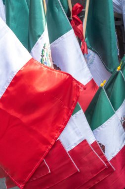 A bunch of flags with red and green stripes hanging together. The flags are from Mexico