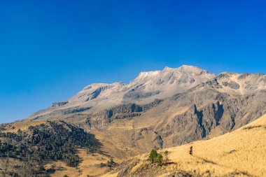 Toprak bir yolda bisiklet süren bir adamın olduğu bir dağ sırası. Gökyüzü açık ve mavi. Iztacihuatl popocatepetl Yanardağ Meksika,