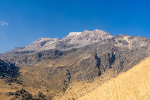 Arka planda açık mavi gökyüzü olan bir dağ sırası. Dağlar karla kaplı ve gökyüzü parlak ve berrak. Iztacihuatl Yanardağı Meksika,