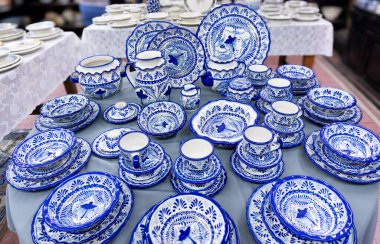 A table full of blue and white plates and bowls. The table is covered with a white cloth. City of Puebla, Mexico, crafts