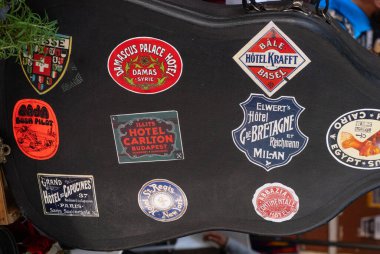 A guitar case is covered with stickers from various hotels and restaurants. The stickers are colorful and diverse, creating a lively and eclectic atmosphere. City of Puebla, Mexico, crafts