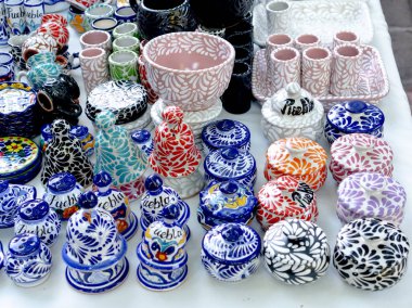 A table full of colorful ceramic items, including bowls, cups, and vases. The items are arranged in a way that creates a sense of abundance and variety. City of Puebla, Mexico, crafts