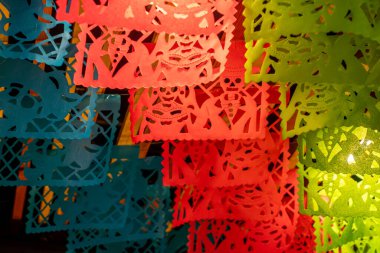 A vibrant display of paper lanterns, each with a unique design and color. Day of the Dead celebration in Mexico, papel picado crafts, offerings, La Catrina