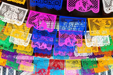 Tavandan sarkan renkli kağıt fenerler. Renkler parlak ve neşeli. Meksika 'da Ölüler Günü kutlaması, papel picado el sanatları, adaklar, La Catrina