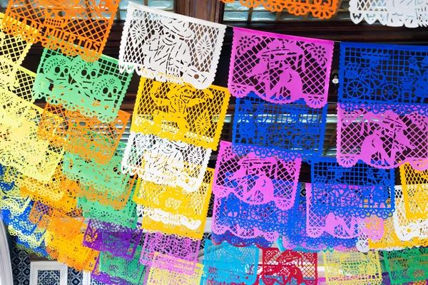 Tavandan sarkan renkli kağıt fenerler. Renkler parlak ve neşeli. Meksika 'da Ölüler Günü kutlaması, papel picado el sanatları, adaklar, La Catrina