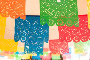 Tavandan sarkan renkli bir dizi kağıt fener. Fenerlerin renkleri ve boyutları farklı. Meksika 'da Ölüler Günü kutlaması, papel picado el sanatları, adaklar, La Catrina