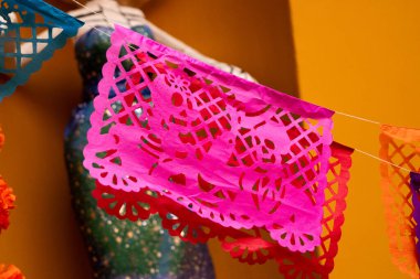 Pembe ve kırmızı bir fener. Kurukafalar ve ipten sarkan çiçekler. Fener bir duvarda asılı. Meksika 'da Ölüler Günü kutlaması, papel picado el sanatları, adaklar, La Catrina