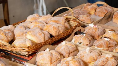 A basket of doughnuts with powdered sugar on top. There are many doughnuts in the basket. Day of the Dead celebration in Mexico, papel picado crafts, offerings, La Catrina