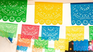 Tavandan sarkan renkli bir dizi kağıt fener. Renkler parlak ve neşeli. Meksika 'da Ölüler Günü kutlaması, papel picado el sanatları, adaklar, La Catrina