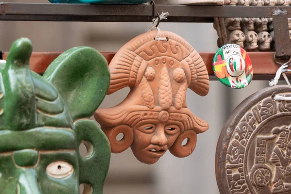 Rafta, bıyıklı bir kafa da dahil olmak üzere bir kil heykel koleksiyonu sergileniyor. Meksika 'da Ölüler Günü kutlaması, papel picado el sanatları, adaklar, La Catrina