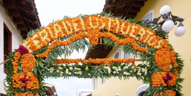 A large archway covered in orange flowers and leaves. The archway is decorated with flowers and leaves. Mexico, zacatlan de las manzanas, puebla, day of the dead mexican tradition