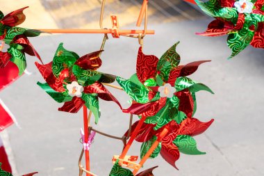 A bunch of windmills with flowers on them are hanging from a wire. The windmills are red, green, and white. Decoration to celebrate Independence Day in Mexico, zocalo