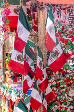 A display of Mexican flags hanging from a pole. The flags are red, white, and green. Decoration to celebrate Independence Day in Mexico, zocalo